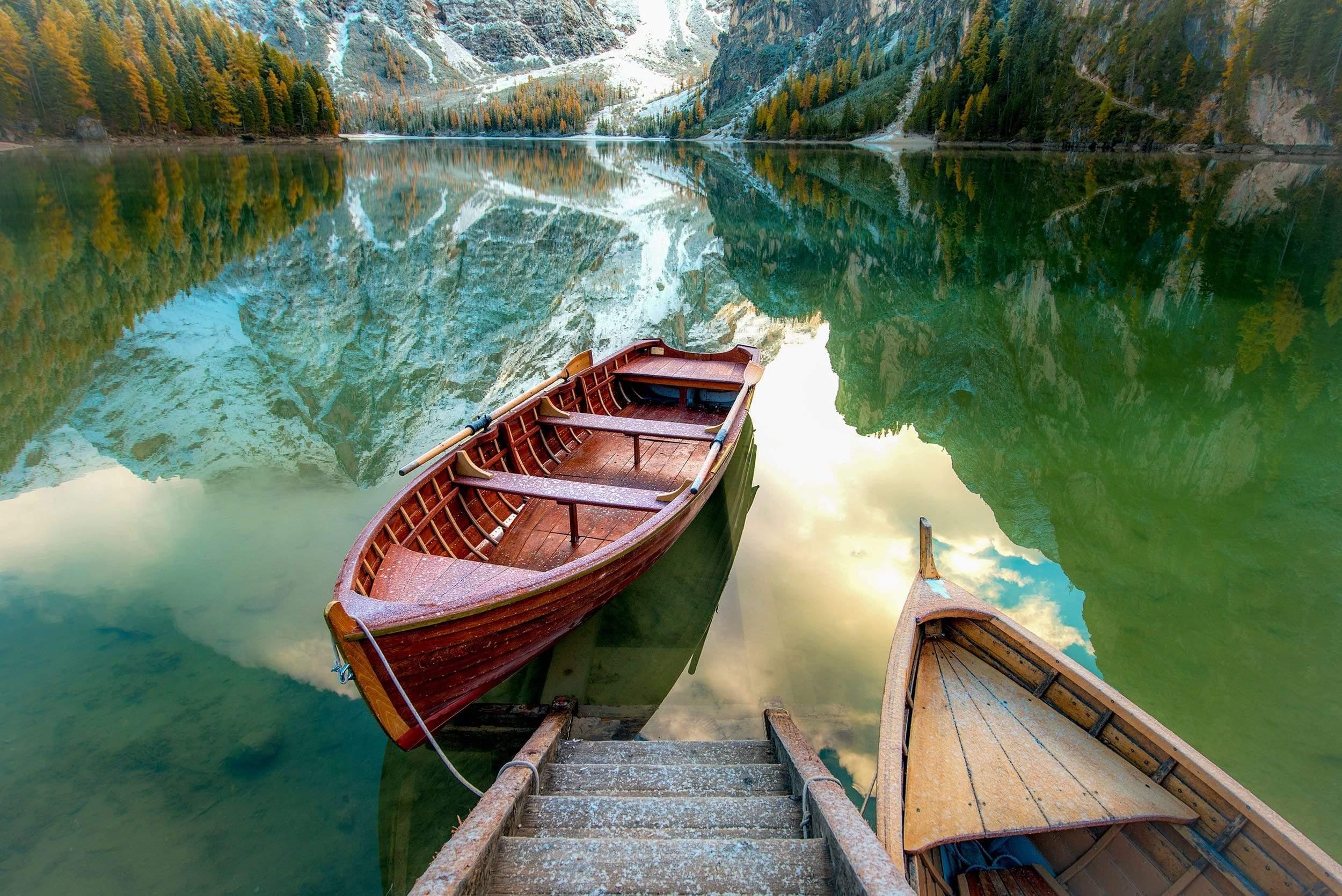 Boat on lake with reflection of mountains wallpaper wall mural