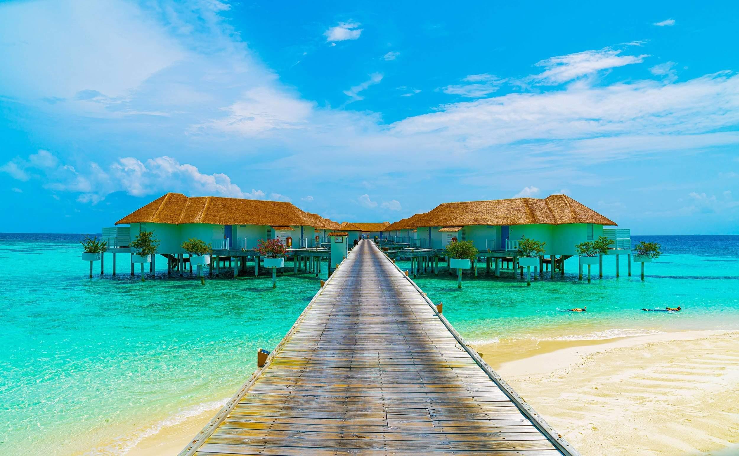 Huts over water with walkway and emerald water