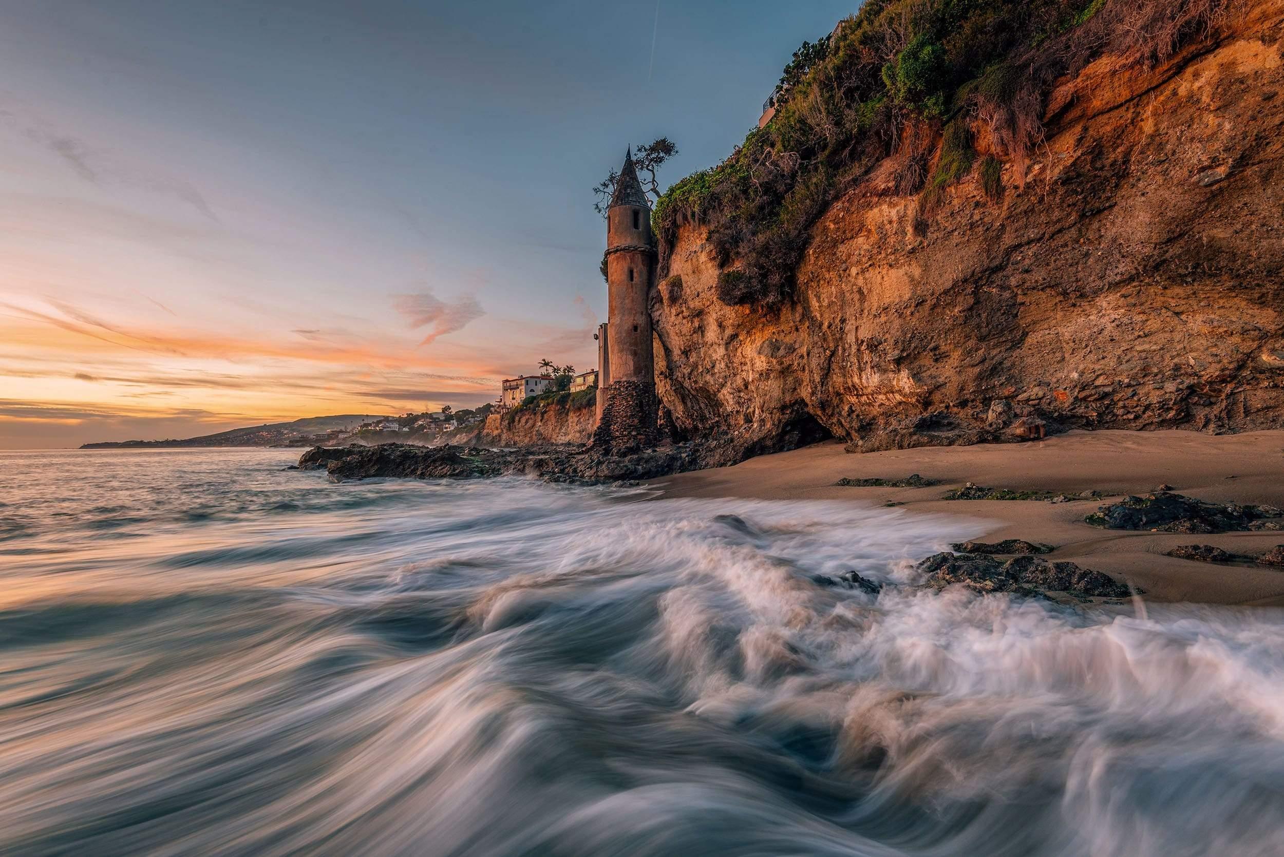 Lighthouse in cliff with blurred waves and sunset