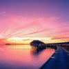 Sunset on Maldives island water villas resort along wooden pier
